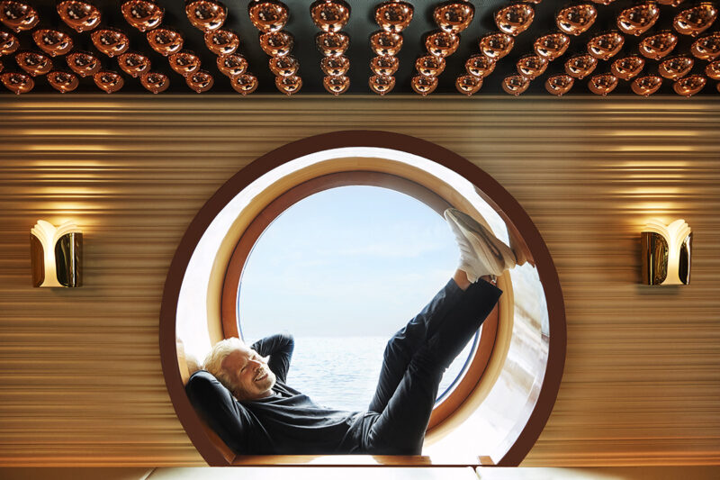 Sir Richard Branson poses in a porthole window in The Wake restaurant onboard Scarlet Lady.  Sir Richard Branson Photoshoot
SCL NY Launch Event
Shoot Date: Sept 14, 2021
Usage: Worldwide/universal unlimited rights in perpetuity for all media including 3rd party usage for all footage and images captured during the shoot. Excluding TV + Broadcast.  Description: Portraits of Sir Richard Branson onboard SCL. 
We also photographed CEO Tom McAlpin.  Deliverables: 10 Retouched images  TEAM
Photographer: Peggy Sirota
http://www.peggysirota.com
Agent: Elyse Connolly  CD: Christian Schrader
Art Buyer / Producer: Kathy Boos